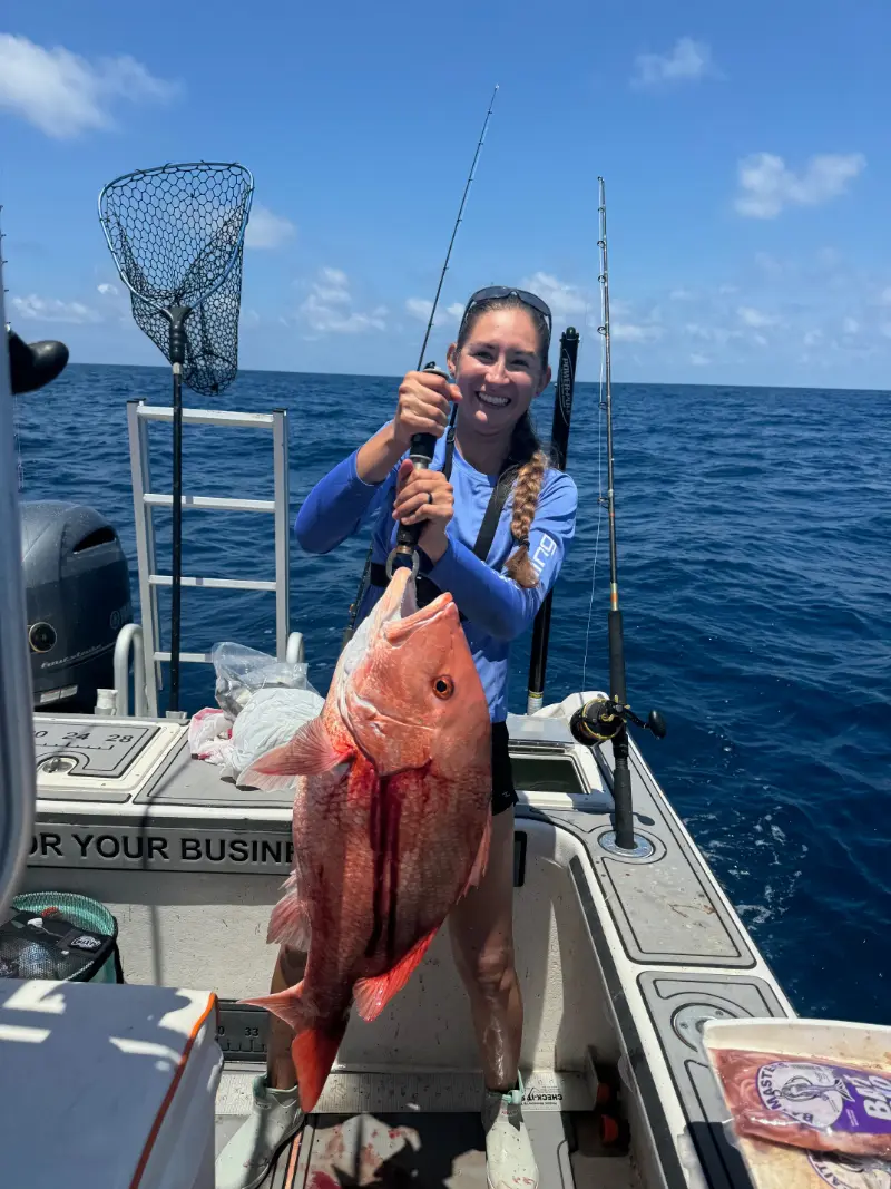 Angler with a braid holding a red snapper by the leader on a Native Charters boat