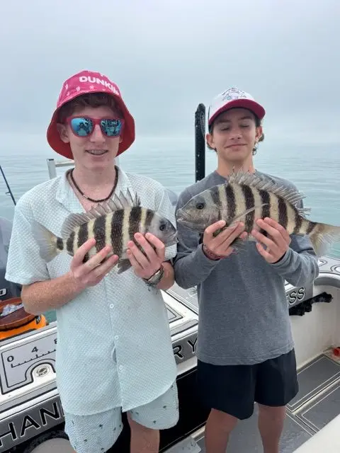 Two teenage anglers each holding a sheepshead on a Native Charters boat