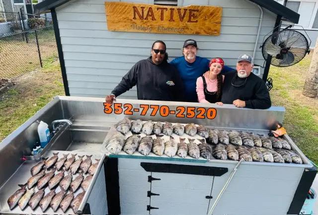 Four anglers at the Native Charters cleaning station behind a table full of sheepshead