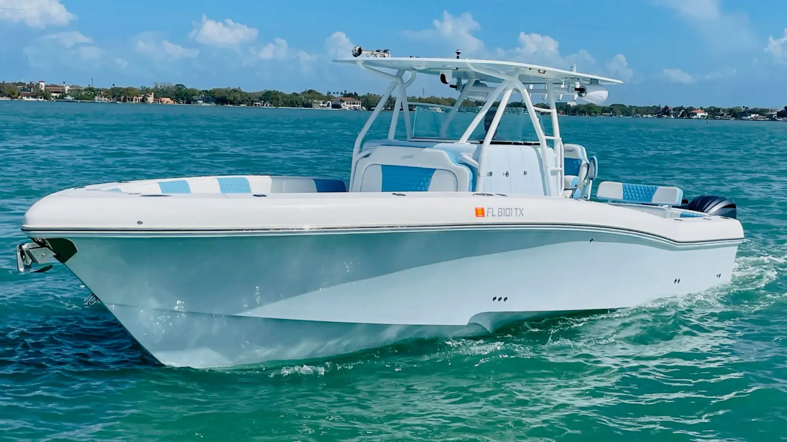 White center console fishing boat with a hardtop and twin outboards idling on calm turquoise water