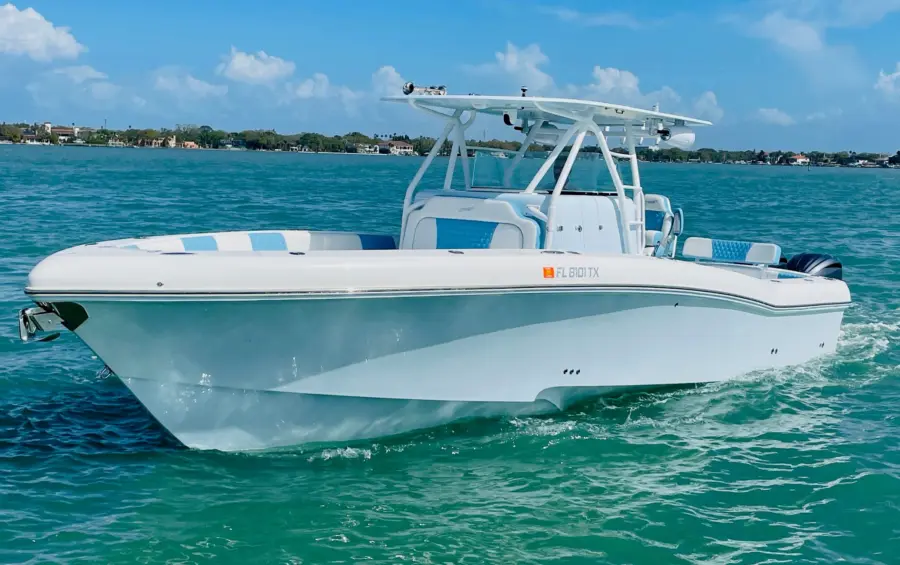 White center console fishing boat with a hardtop and twin outboards idling on calm turquoise water