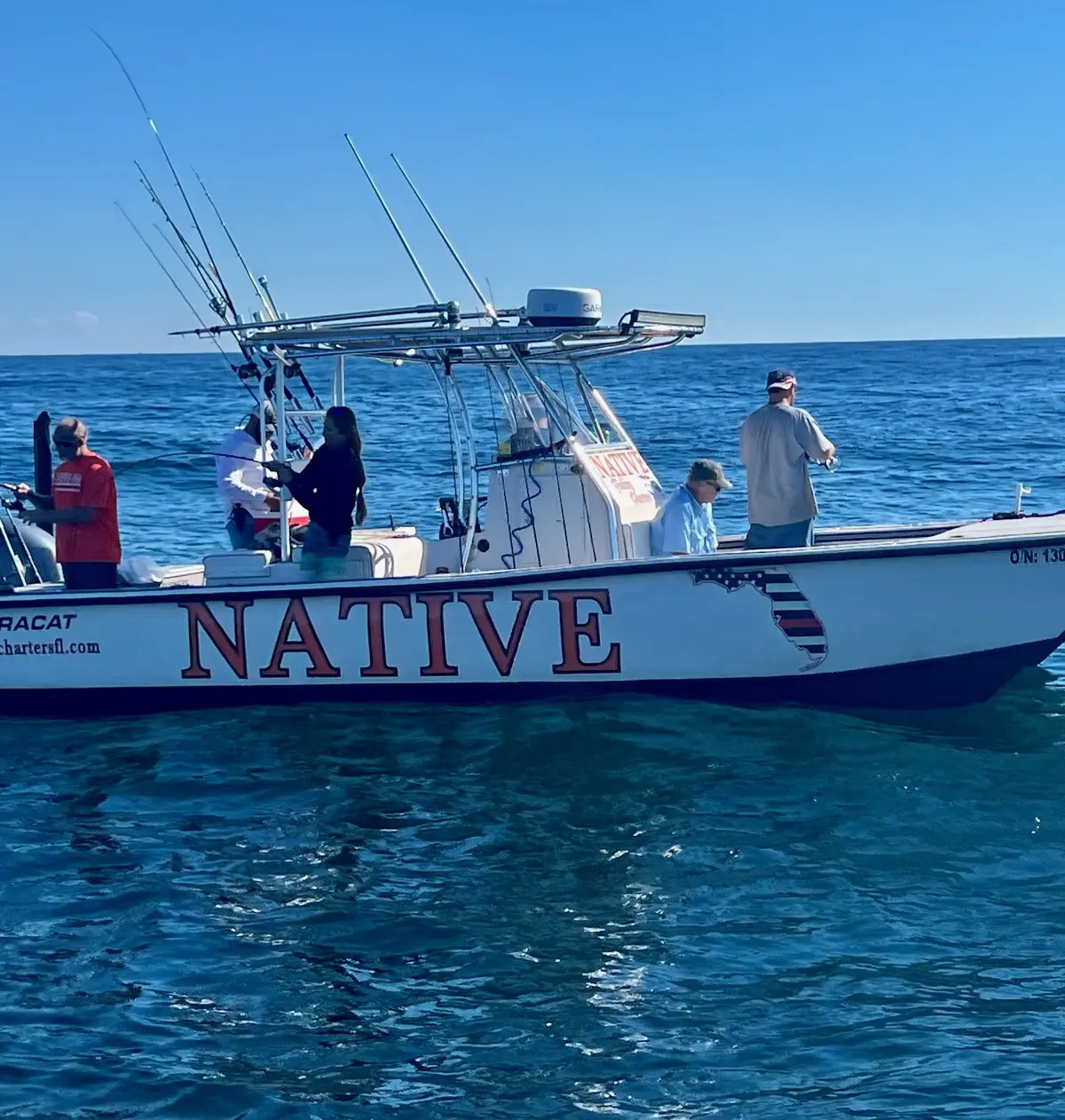 The Native Charters 27-foot AmeraCat catamaran on calm blue Gulf water with five anglers fishing from the deck