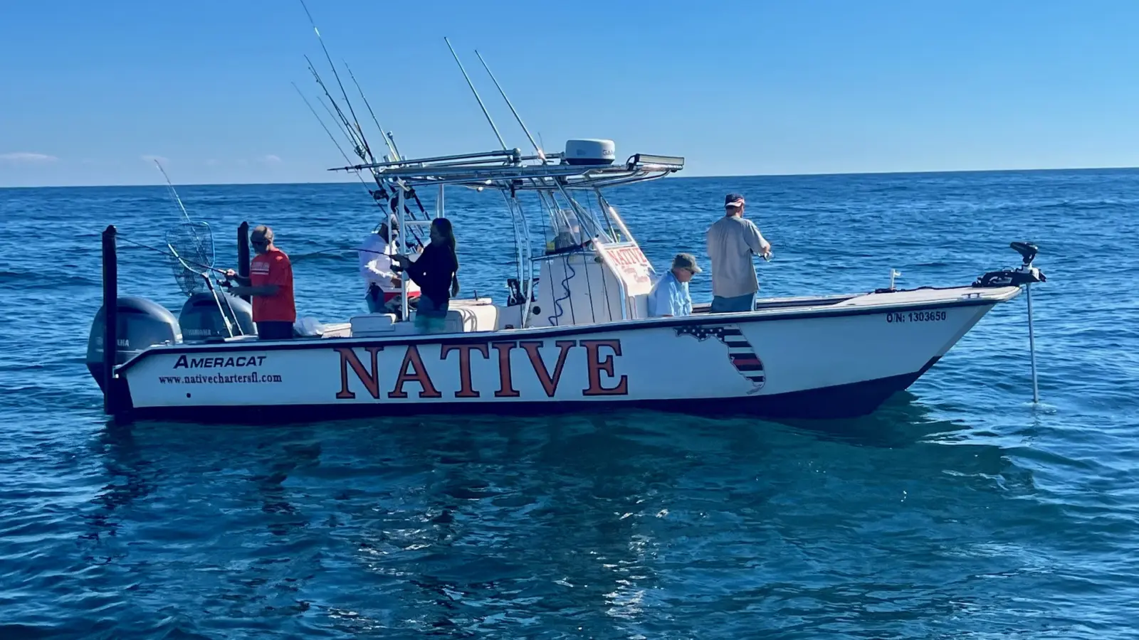 The Native Charters 27-foot AmeraCat catamaran on calm blue Gulf water with five anglers fishing from the deck